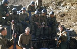 Military men in uniforms watching musicians in the back of a truck