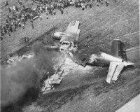 black and white photo of a plane crash in a farm field