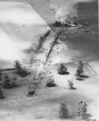 black and white photo of a plane crash in a farm field