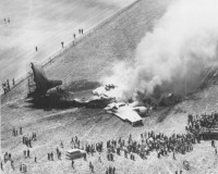 black and white photo of a plane crash in a farm field